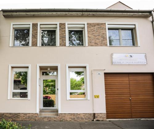 een wit huis met een bruine garage bij Balance Apartman Debrecen in Debrecen