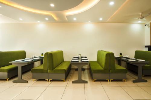 a restaurant with two tables and green chairs at Hotel The Katra Avenue in Katra