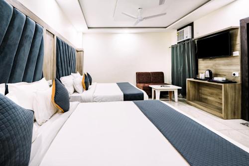 a hotel room with two beds and a television at Hotel The Katra Avenue in Katra