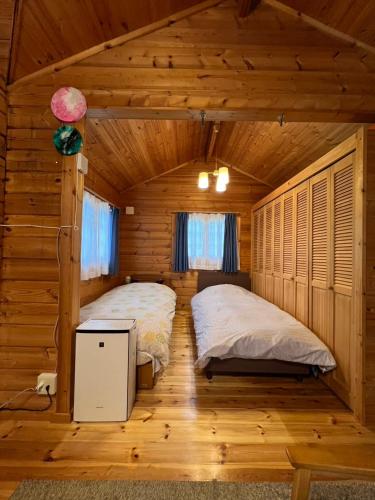 a bedroom with two beds in a log cabin at コテージコッタロ in Gojikkoku