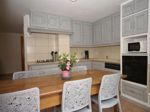 a kitchen with a wooden table and white cabinets at Captivating Holiday Home in Les Vans with Pool in Les Vans