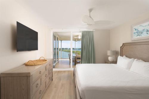 a bedroom with a bed and a television and a balcony at Hawks Cay Resort in Marathon