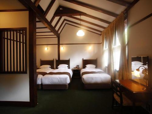 a hotel room with two beds and a window at Unzen Kanko Hotel in Unzen