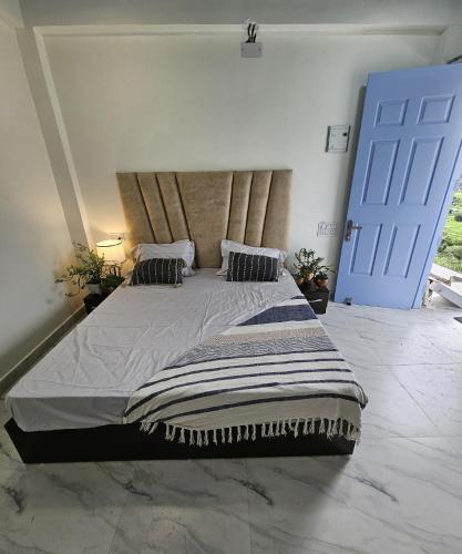 a bedroom with a large bed with a blue door at Jab We Met-Bir Billing in Baijnāth