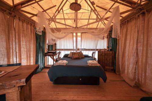 a bedroom with a bed in a room with curtains at Slow Life Camping Venta del Moro in Venta del Moro
