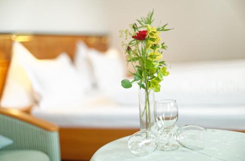 a vase with a rose and two glasses on a table at Hotel Edelweiss in Maria Alm am Steinernen Meer