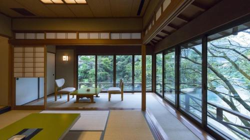 a room with large windows and a table and chairs at Myoken Ishiharaso in Kirishima