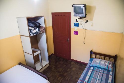 クリチバにあるHotel Pinheirinhoのベッド1台、壁掛けテレビが備わる小さな客室です。