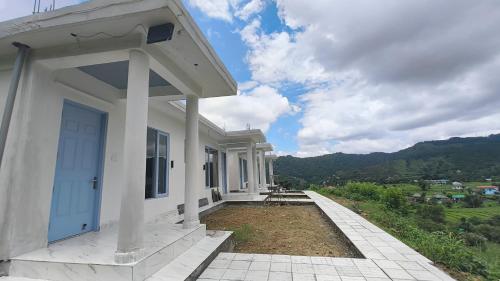 a white house with a blue door and a view at Jab We Met-Bir Billing in Baijnāth
