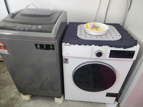 a washing machine with a bowl on top of it at Homestay Zaishazali in Gelugor