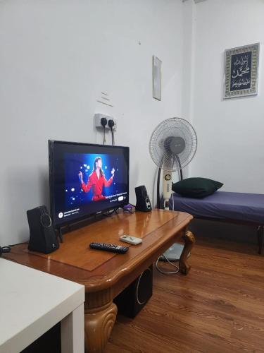 a living room with a table with a television on it at Homestay Zaishazali in Gelugor