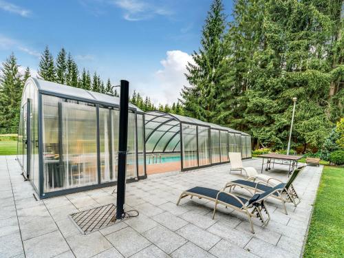 una casa de cristal con 2 sillas y una mesa en Luxurious Apartment in Jägersgrün with Saunas, en Jägersgrün