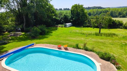 a swimming pool in a yard with a field at The Farmhouse La Drutière in Saint-Sauveur-de-Carrouges