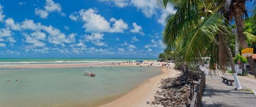 a beach with people and a boat in the water at Serhs Villas Da Pipa Hotel in Pipa