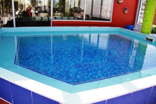 ein großer Pool mit blauen Bodenfliesen in der Unterkunft Hotel California Panama in Panama-Stadt