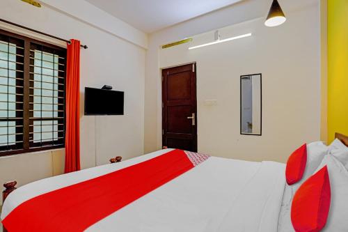 a bedroom with a red and white bed in a room at Hotel O Parppidam Residency Kazhakuttam Railway Station in Kazhakuttam