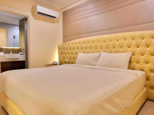 1 dormitorio con 1 cama grande y cabecero amarillo en Ritzton Hotel, en Johor Bahru