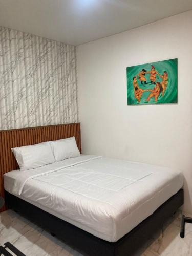 a bed in a bedroom with a painting on the wall at Hotel Sanrina Kuta Bali in Kuta