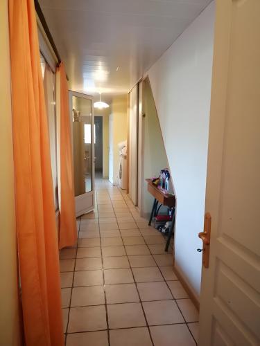 a hallway with an orange door and a tile floor at Gîte À La Campagne in Bourdeaux