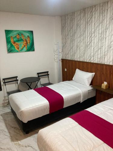 a bedroom with two beds and a table at Hotel Sanrina Kuta Bali in Kuta