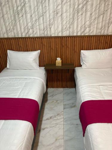 two beds sitting next to each other in a room at Hotel Sanrina Kuta Bali in Kuta