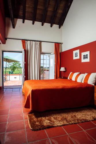 a bedroom with a bed with a red wall at Quinta da Gafaria in Santarém
