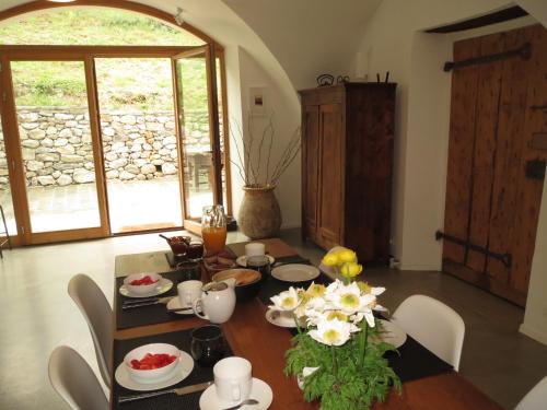 - une salle à manger avec une table et des fleurs dans l'établissement La Maison Abeil, à LʼArgentière-la-Bessée