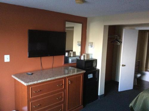 a hotel room with a kitchen with a microwave and a television at Royal Inn in Tonawanda