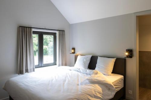 a bedroom with a large white bed with a window at Comfortabele groepswoning voor 8 met ruimte tuin in Turnhout