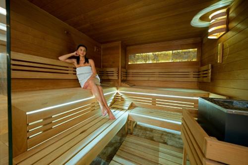 a woman is sitting in a sauna at Hotel Bartoš in Frenštát pod Radhoštěm