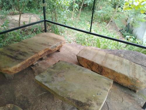 two stone benches sitting next to a rail at Birds rock villa Sinharaja in Deniyaya
