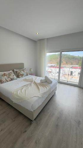 a white bedroom with a bed and a large window at Vila D`arte Vila de Rei in Vila de Rei