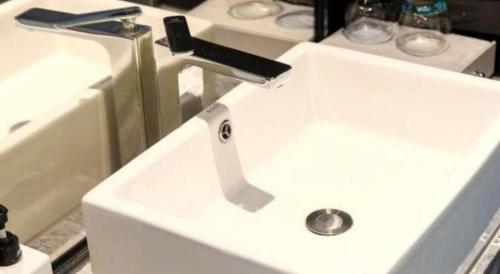 a white sink with a faucet in a bathroom at Echarm Hotel Xiangyang Erqi in Xiangyang