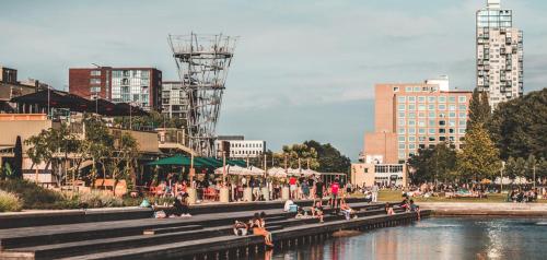 a group of people sitting on benches next to a body of water at Mercure Hotel Tilburg Centrum in Tilburg