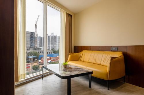 a living room with a yellow couch and a large window at Saltstayz Premier - Manesar & Sector 86 in Gurgaon
