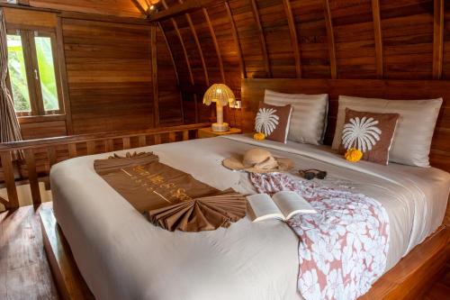 un letto con un cappello e un libro sopra di Yama Villa & SPA Ubud a Payangan
