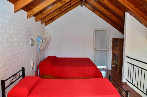 a bedroom with two red beds and a window at Complejo Las Hoyas in Villa Carlos Paz