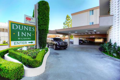 a sign in front of a building with a car at Dunes Inn - Wilshire in Los Angeles