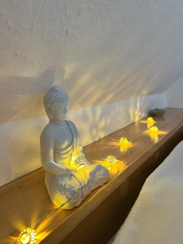 a buddha statue sitting on a shelf with lights at Marosi Ház in Nagymaros