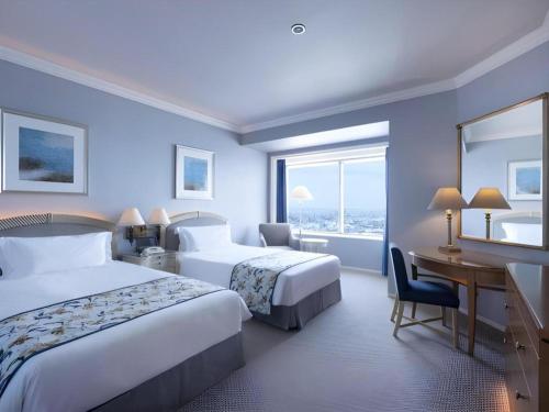 a hotel room with two beds and a desk at Yokohama Royal Park Hotel in Yokohama
