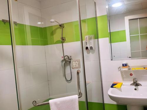 Un baño verde y blanco con ducha y lavabo. en 7 Days Inn Guiyang Qingzhen Dongmenqiao Zhijiaocheng, en Dongmenqiao