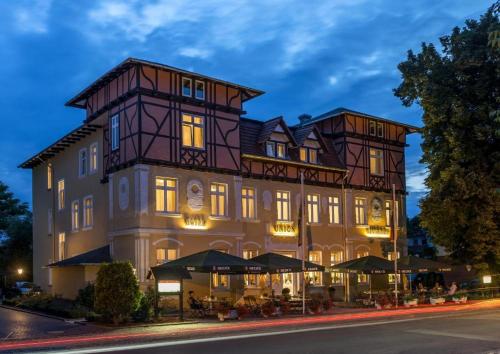 a large building with tables and umbrellas in front of it at Hotel Union Salzwedel in Salzwedel