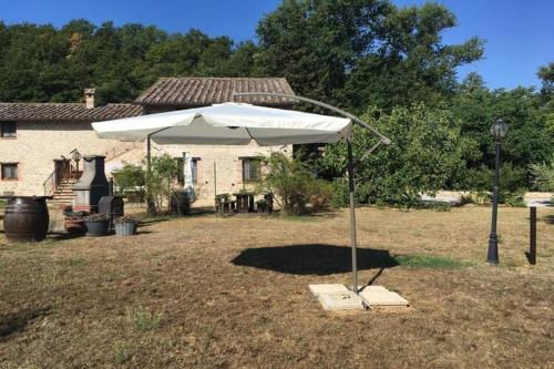 a white umbrella in a yard in front of a house at Modern Holiday Home in Pietrafitta Umbria with Garden in Pietrafitta