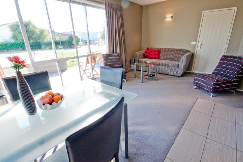 a living room with a table and chairs at Bay Breeze Accommodation in Cooks Beach