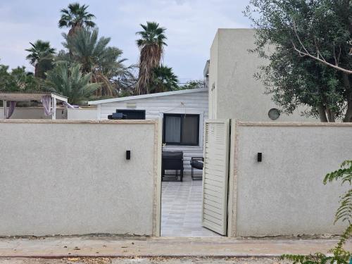 two gates to a house with palm trees in the background at Zimmer Belev HaKikar- Dead sea in Neʼot HaKikar