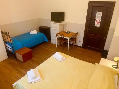 a small room with two beds and a table with a television at Il Cielo di Lucio in Pisa