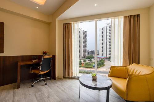a hotel room with a couch and a desk and a window at Saltstayz Premier - Manesar & Sector 86 in Gurgaon