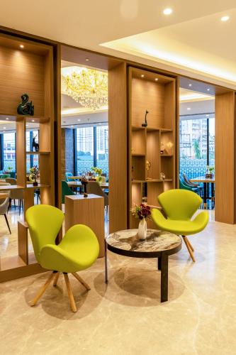a lobby with green chairs and a table at Saltstayz Premier - Manesar & Sector 86 in Gurgaon