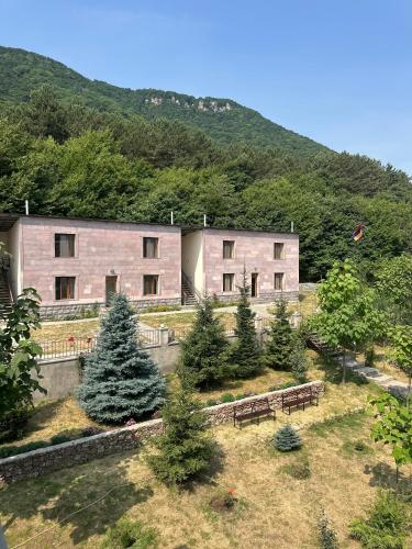 a building with benches in front of a mountain at Yeghevnut Hotel in Goris
