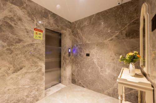 a bathroom with marble walls and a vase of flowers on a table at Saltstayz Premier - Manesar & Sector 86 in Gurgaon